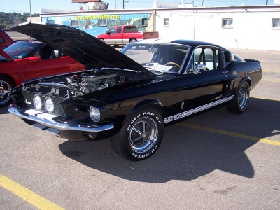 1972 Ford Ranchero - A black 1967 Shelby GT500 is displayed with its hood open, parked beside a red vehicle.