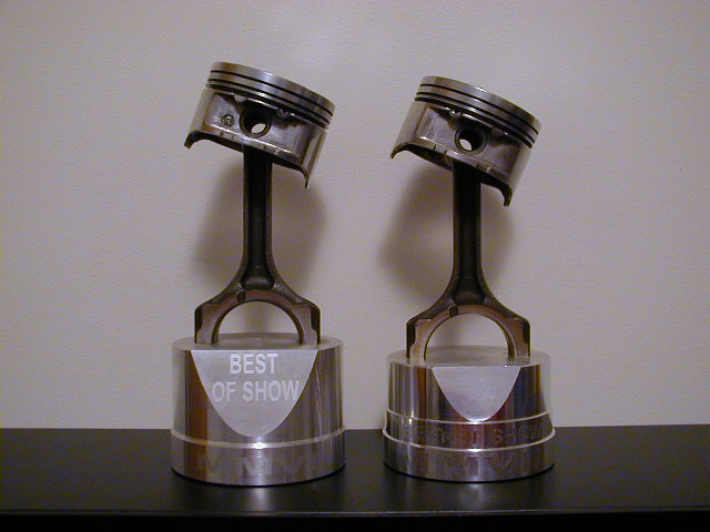 Two pistons mounted on trophies labeled 'BEST OF SHOW'