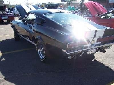 1972 Ford Ranchero - A black 1968 Ford Mustang fastback with white racing stripes is parked outdoors, with its hood open.