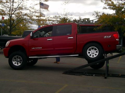 1985 Ford Bronco - A red pickup truck with V8 TITAN badging is shown on a lift.