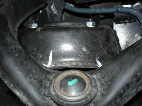 2005 Nissan Titan - This image shows a close-up view of a vehicle's suspension system, focusing on a component with bolts and white markings.
