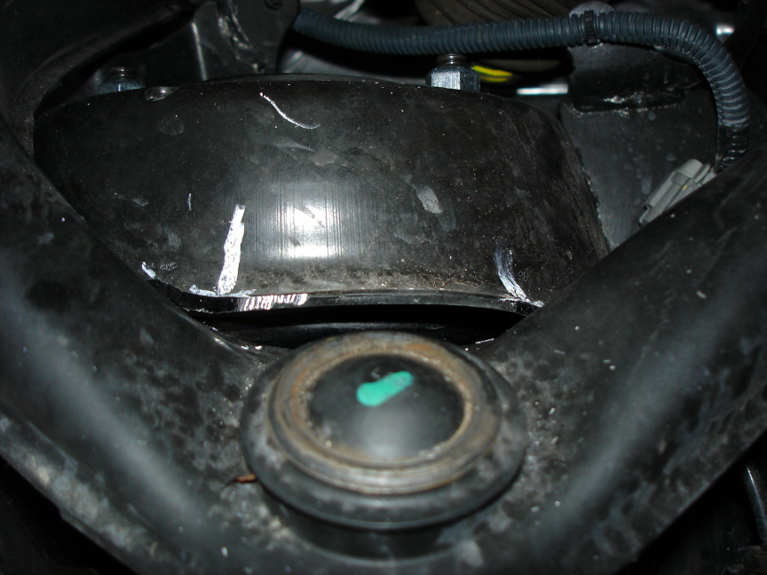 Black suspension component with rubber mount and green center plug
