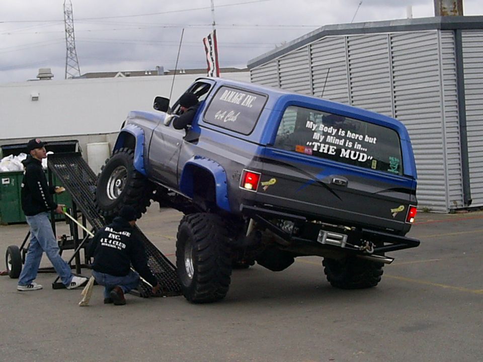 Blue 1985 Ford Bronco with lifted suspension and off-road tires, rear view