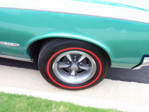 1967 Pontiac Lemans - Close-up of the side view of a teal 1967 Pontiac Lemans, highlighting its fender and wheel with a red stripe tire.