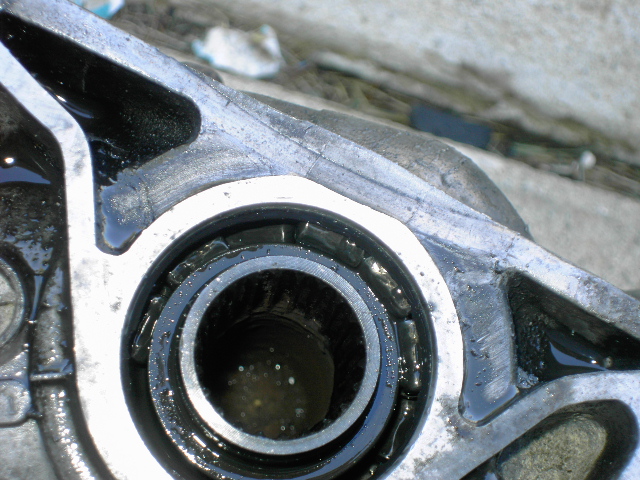 Close-up of an oily aluminum housing with an exposed bearing race and dark bore