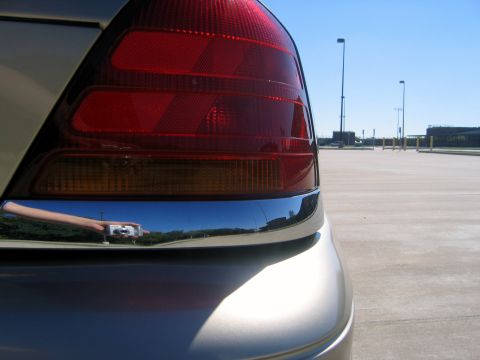 2000 Ford Crown Victoria - The rear of a car is shown, with a reflection of a person holding a camera in the chrome trim.