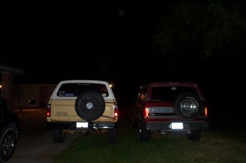 1978 Dodge Power Ram - Two SUVs are parked in a driveway at night, each with a spare tire mounted on the rear.