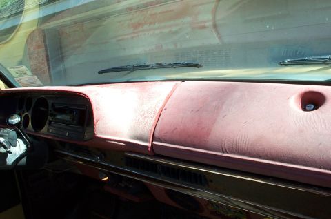 1978 Dodge Power Ram - The interior of a pickup truck shows a worn red dashboard with a radio and air vents.