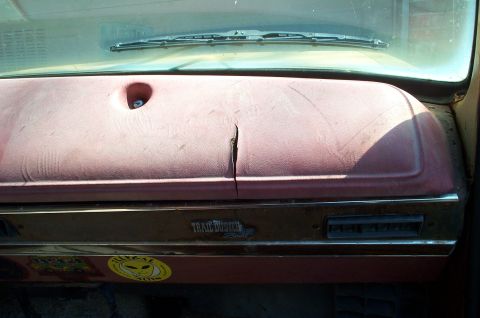 1978 Dodge Power Ram - Interior view of a cracked dashboard with a 'Trail Duster' emblem and a sticker.
