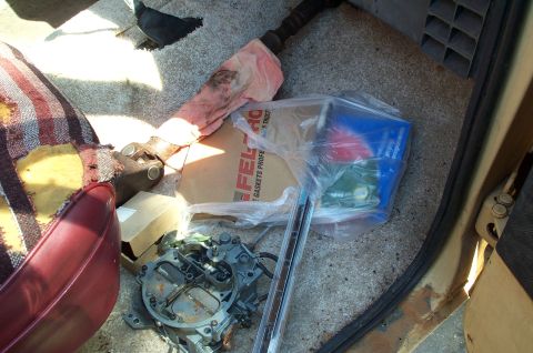 1978 Dodge Power Ram - The interior of a vehicle contains a carburetor, driveshaft, and a box of Fel-Pro gaskets, suggesting recent work or parts storage.