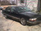 1994 Ford Crown Victoria - This dark sedan, likely from the mid-1990s, is parked outdoors on a concrete surface.