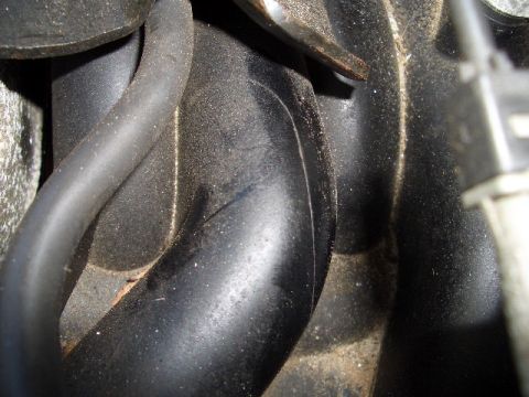 1999 Ford Crown Victoria - Close-up view of engine hoses and black plastic housing, with "Supermotors.net" watermark visible.