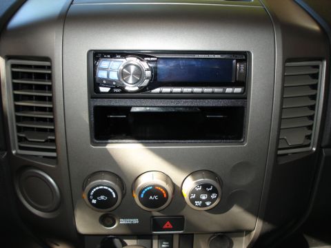 2005 Nissan Titan - The dashboard features an aftermarket stereo unit installed in the upper dash area, with climate control knobs below.