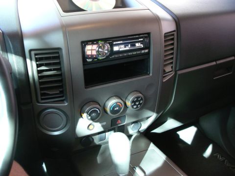2005 Nissan Titan - The center console of a 2005 Nissan Titan features an aftermarket stereo system and a CD on top.
