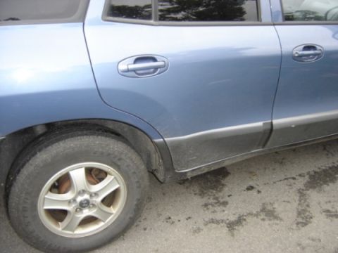 1999 Ford Taurus - Side view of a blue SUV, revealing its rear door, wheel, and protective black trim along the lower body.