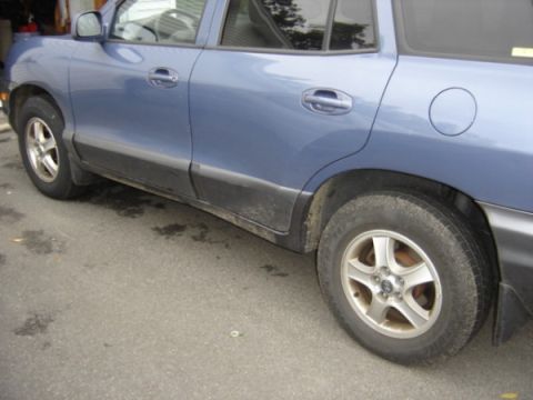 1999 Ford Taurus - Side view of a blue SUV, likely a Hyundai Santa Fe, parked outdoors.
