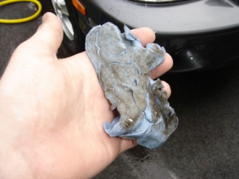 1999 Ford Taurus - A hand holds a used clay bar, showing the contaminants it has picked up from a surface.