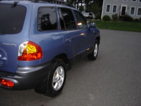 1999 Ford Taurus - Blue Hyundai Santa Fe SUV seen from the rear quarter angle on a paved surface.