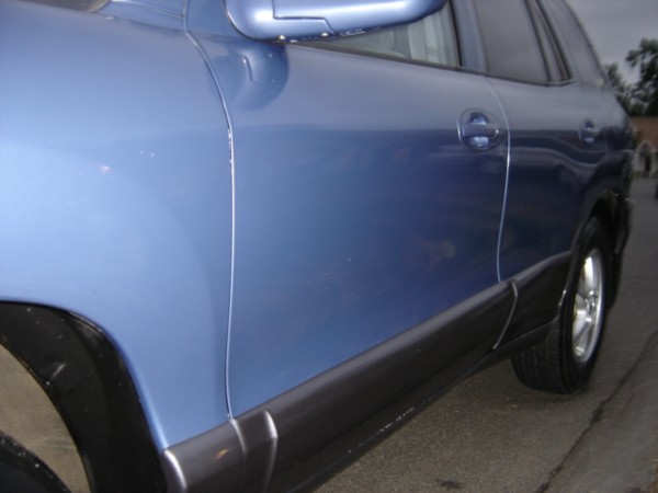 Side view of a blue SUV showing the door, black trim, and wheel