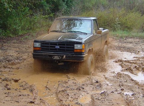 1989 Ford Ranger - This Ford Ranger is navigating a challenging muddy terrain, kicking up dirt and water.
