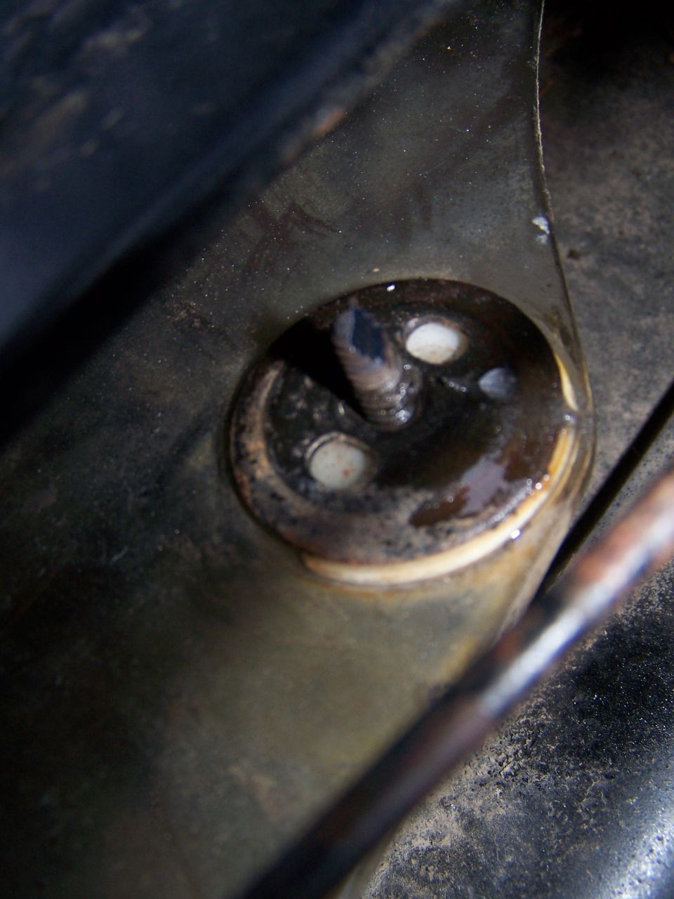 Close-up of a rusty metal bracket with a bolt and rubber grommets
