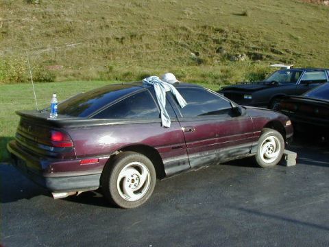 1994 Ford Probe - This maroon 1994 Ford Probe is seen from the side, with a blue bottle resting on its trunk.
