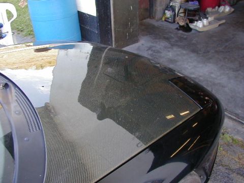 1994 Ford Probe - The front corner of a car with a carbon fiber hood is visible, parked in a garage.