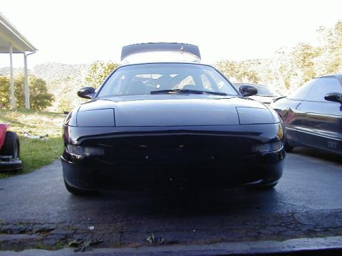 1994 Ford Probe - A black coupe with pop-up headlights is parked in front of another car.