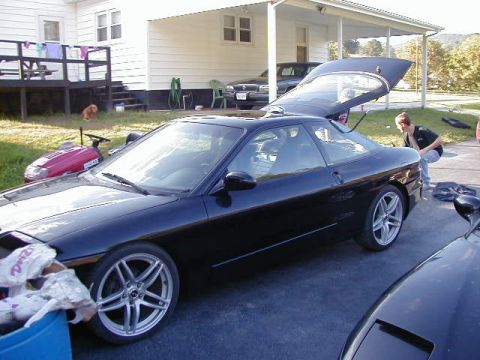 1994 Ford Probe - A black 1994 Ford Probe is parked outside a house with its trunk open, while a person looks into it.