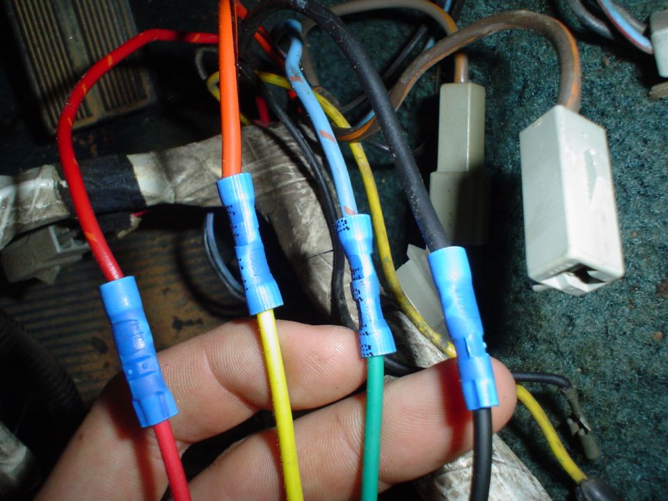 Hand connecting wires with blue crimp connectors to a vehicle wiring harness