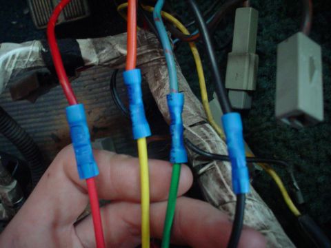 1984 Ford Bronco - Close-up of a hand making electrical connections in a vehicle's wiring.