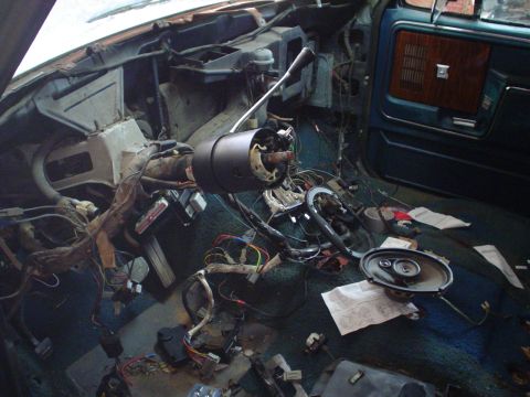 1984 Ford Bronco - The interior of a vehicle is disassembled, with wiring exposed and parts scattered across the floor.