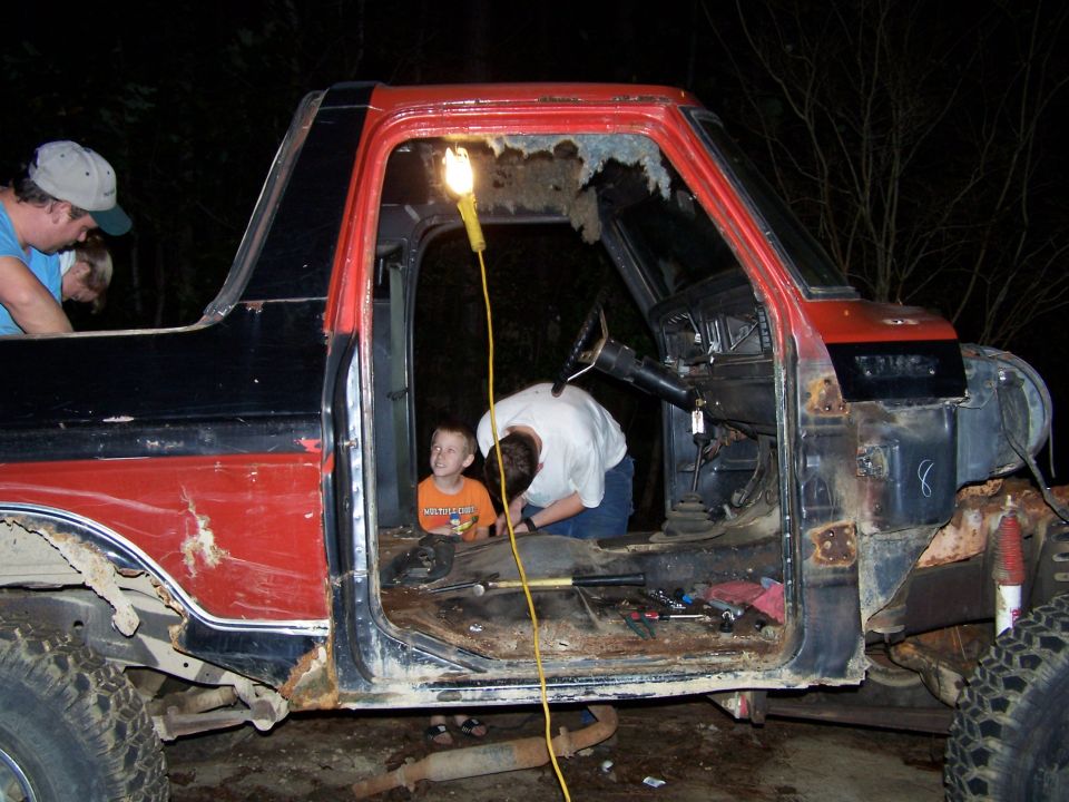 Red and black truck cab interior, open doors, people working on project