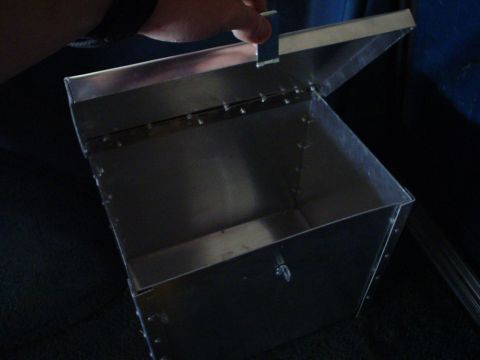 1984 Ford Bronco - A metal box is shown inside a vehicle, with a hand reaching for its lid.