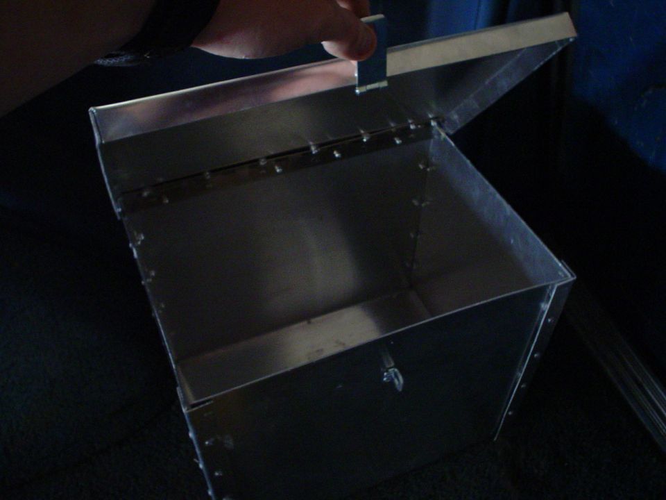 Metal box with hinged lid, riveted construction, inside a vehicle