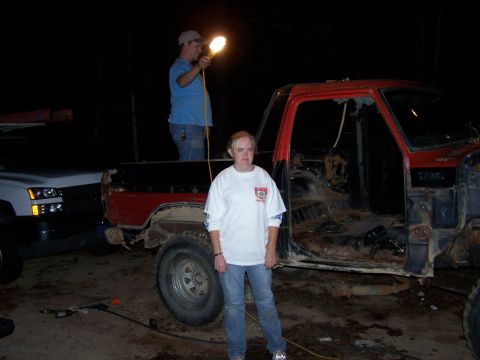 1979 Ford F-150 - A red pickup truck is partially disassembled, with a woman standing in front of it and a man holding a light in the background.