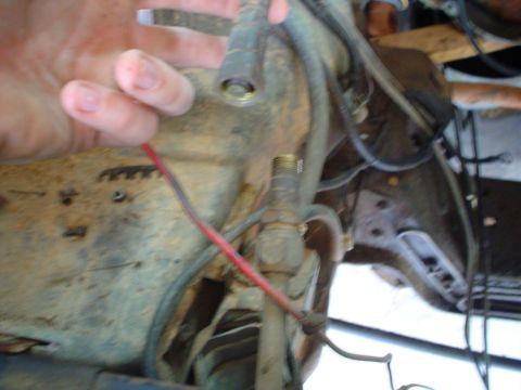 1984 Ford Bronco - Close-up of engine bay components with a hand manipulating a wire.
