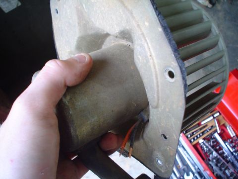 1984 Ford Bronco - A blower motor assembly with exposed wires and fan blades is held for inspection, with tools visible in the background.