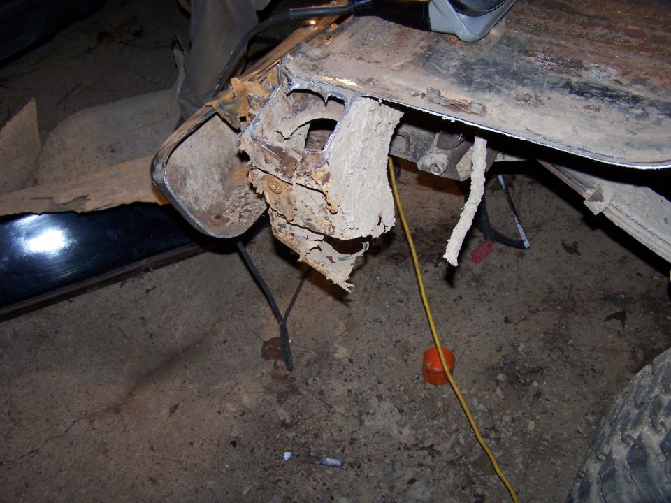 Heavily rusted metal frame section of a vehicle, showing damage and decay