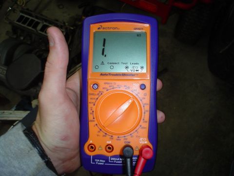 1984 Ford Bronco - A multimeter is held in a hand, displaying a reading and instructions.