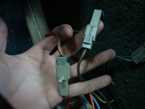 1984 Ford Bronco - Close-up of a hand holding two disconnected electrical wiring harnesses.