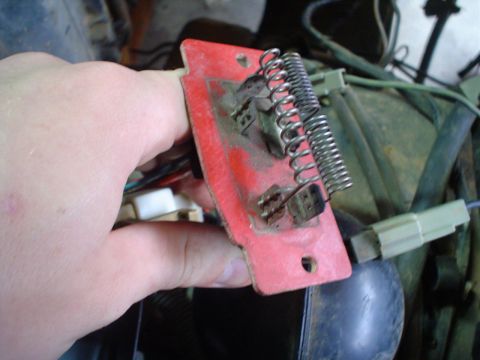 1984 Ford Bronco - A red blower motor resistor with visible spring coils and electrical connectors is held in a hand.