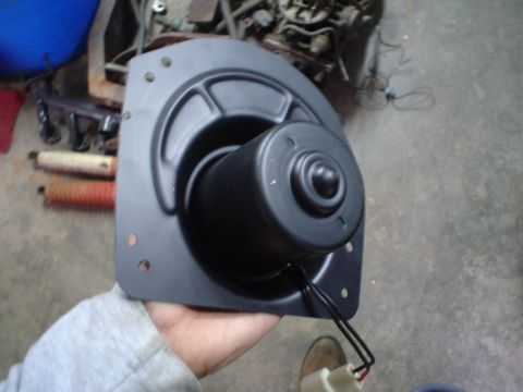 1984 Ford Bronco - A person holds a black blower motor assembly, likely for a vehicle's HVAC system.