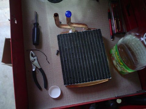 1984 Ford Bronco - Heater core and tools laid out on a textured surface inside a red toolbox.
