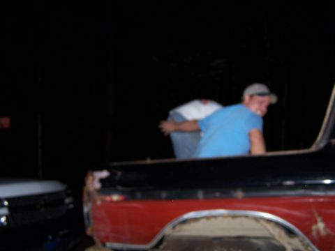1979 Ford F-150 - Two people are in the bed of a red pickup truck at night, with another vehicle nearby.