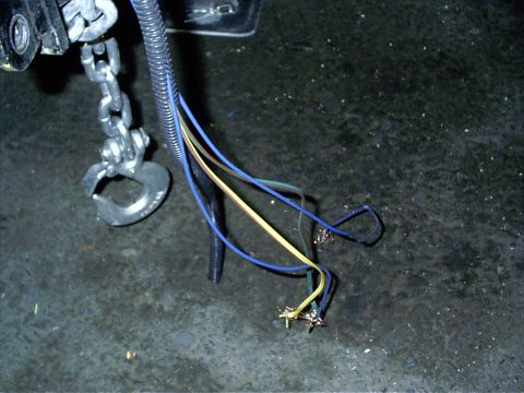 1979 Ford Bronco - A close-up shows a trailer hitch hook and several exposed electrical wires, suggesting a connection point for towing.
