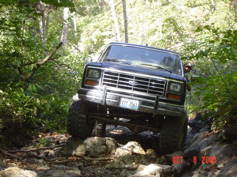 1986 Ford Bronco - This 1980s Ford Bronco tackles a challenging, rocky path through a dense forest.