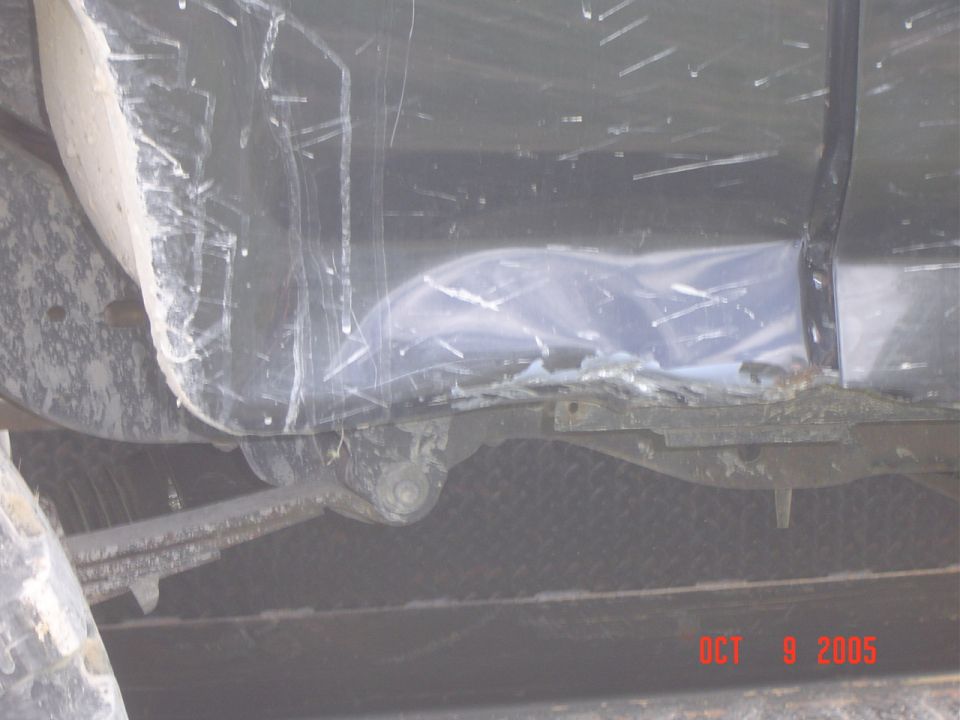 close-up of vehicle's undercarriage, showing suspension and body damage