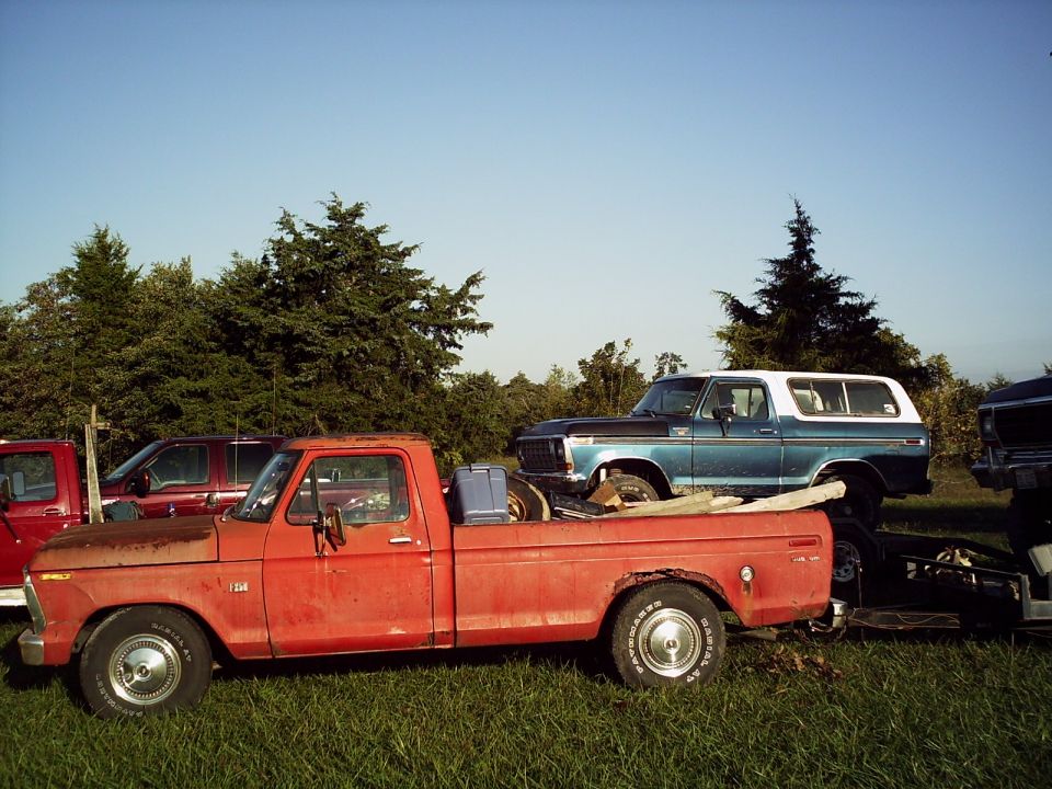 Blue and white Ford Bronco parked next to a red pickup truck