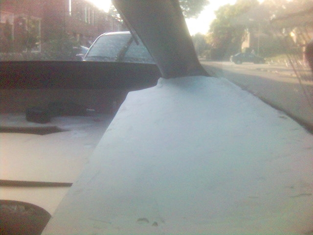 View from inside a car, looking through the windshield at a street scene. A large part of the dashboard is in the foreground